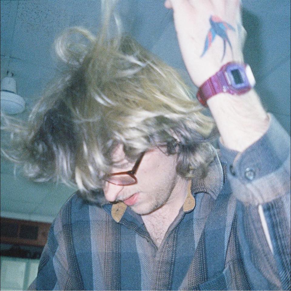 A blonde man in the midst of shaking his head around